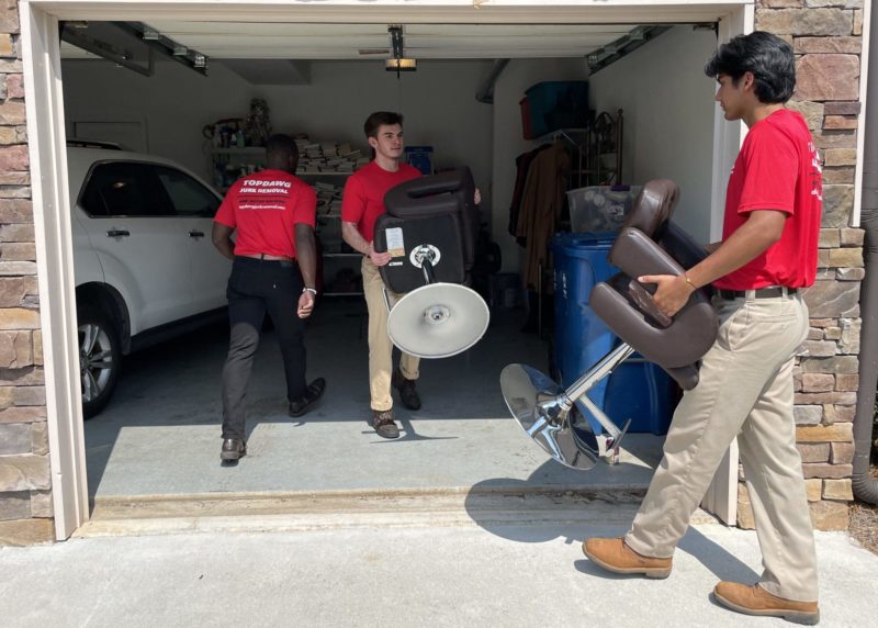 Junk removal crew hauling chairs from garage