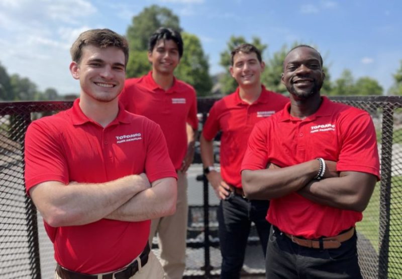 topdawg junk removal crew smiling in front of junk trailer