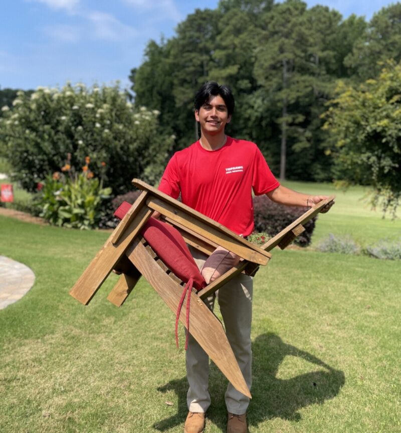 TopDawg Junk Removal professional carrying an old chair off a lawn during large item pickup services