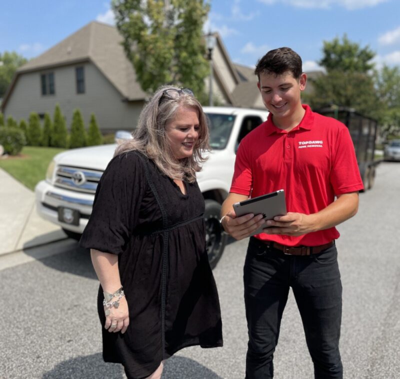 TopDawg Junk Removal professional holding a table and explaining the large item removal process to a happy customer